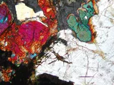 Mikroskopfoto av en bergart. Färgerna uppkommer i polariserat ljus beroende på kristallers speciella optiska egenskaper.